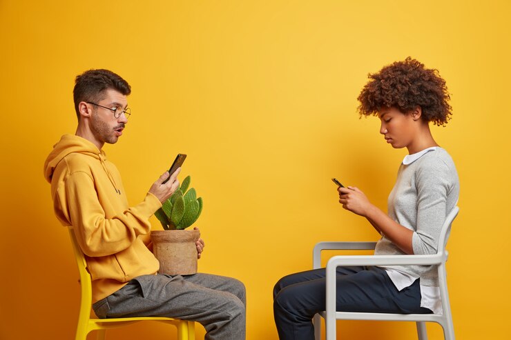 addicted-multiracial-couple-use-their-mobile-phones-online-communication-sit-opposite-each-other-chairs-have-internet-addiction-spend-free-time-home